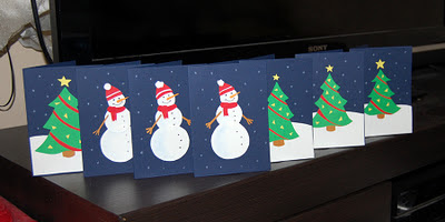 Snowmen army in the forest of Christmas trees. Photo of hand-made Christmas cards.