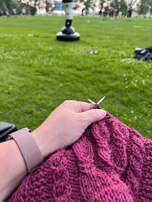 The photo shows Sarah's knitting project during football practice.  The field and team is in the background