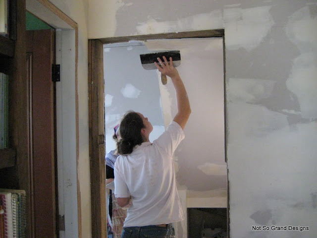 Looking past the bathroom door and through the recently created doorway beneath the top of the staircase: Blick, plastering the underbelly of the staircase.