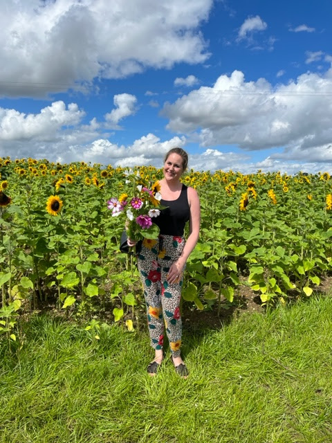 a woman holding a bouquet of flowers in a field of sunflowers
