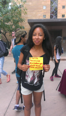 Photo of an ASU student holding her "Why I Write" square for our paper quilt. The square reads "I write because 62 million girls don't have that chance."