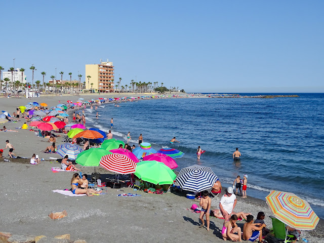 Playa con muchas sombrillas y turistas con el mar a su frente