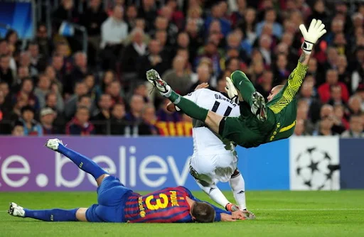 Gerard Piqué lies on the ground after getting knocked down by his own goalkeeper Víctor Valdés