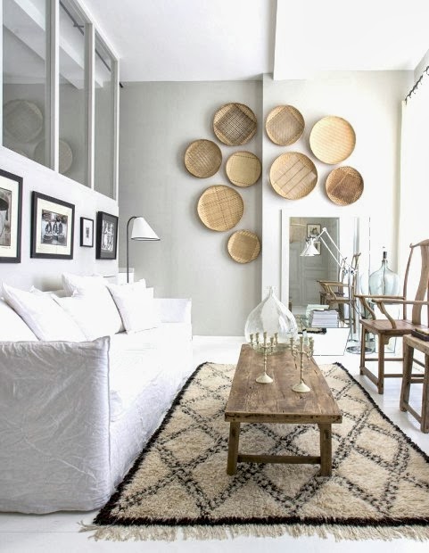 Small white living room in an apartment in France with a reclaimed wood coffee table, slip covered sofa and decorative baskets