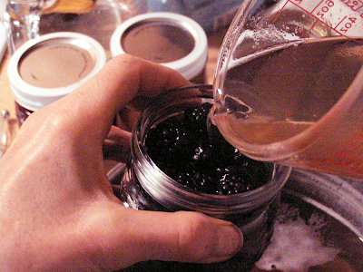 Hands Pouring Hot Syrup into Jar of Blackberries with Measuring Cup