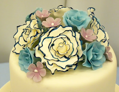 There are large white gumpaste roses tipped with navy blue light blue roses