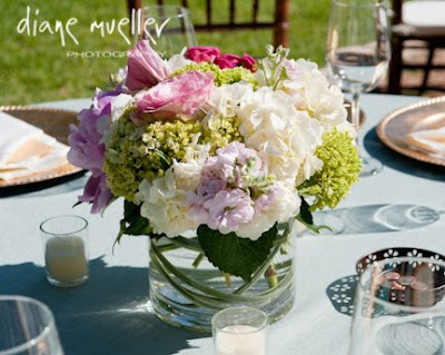 Low wide cylinder vases with grass swirls and a fluffy mix of wedding 
