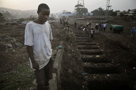 A grave digger looks at freshly dug graves for Ebola victim at a cemetery in Freetown, Sierra Leone, December 17, 2014. REUTERS/Baz Ratner