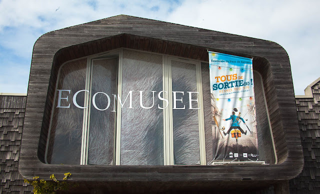 Entrée du parc de l'écomusée du pays rennais. Façade en bois et verre, qui ressemble au contour d'une maison.