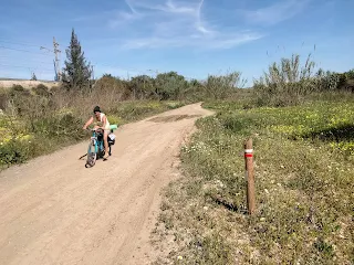 Aim'jie redes her bicycle on a broad hiking trail, on the side a white red mark.