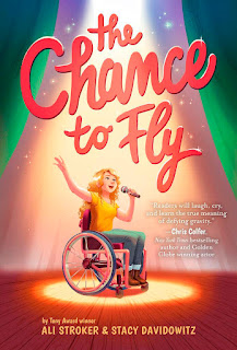 Book cover with the drawing of white girl in a wheelchair. She is holding a microphone and singing with bright spotlight from above.