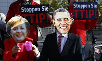 Protesters wear masks of Barack Obama and Angela Merkel as they demonstrate against TTIP free trade agreement. (Photograph Credit: Wolfgang Rattay/Reuters) Click to Enlarge.