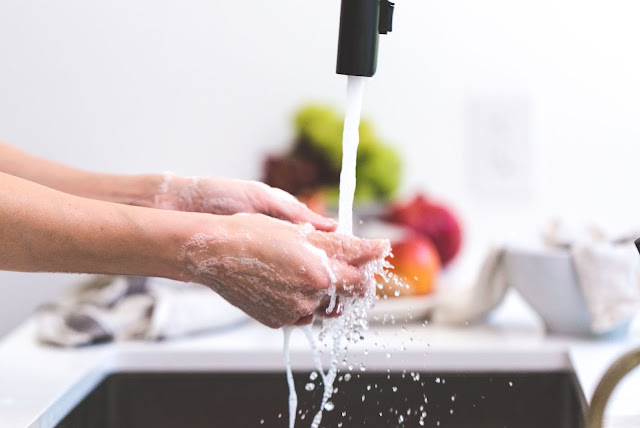 Person washing hands with tap water