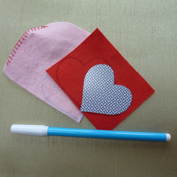 Water soluble blue fabric marker pen tracing around a heart template onto red and pink felt fabric