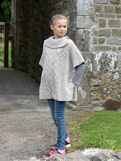 Girl is modelling in hand knitted poncho, made with various cables combination and textured stitches