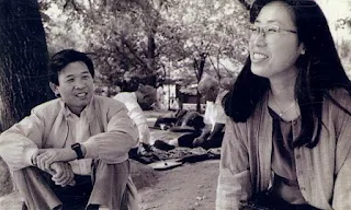 A black-and-white photograph of Jeong Tae-chun and Park Eun-ok, a Korean musician couple, smiling and chatting in a park.