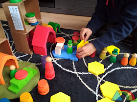 Niño jugando con nins de Joguines Grapat y casitas de Grimms Wooden Toys