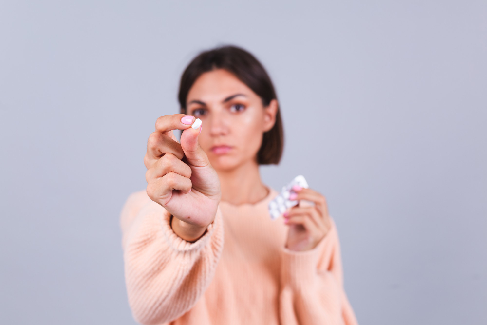 woman holding pill in front of her between fingers