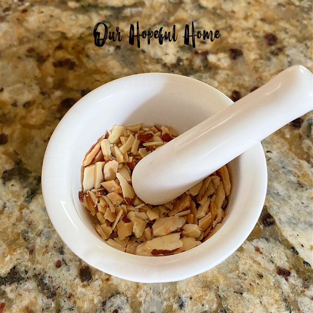 white porcelain mortar and pestle filled with sliced almonds