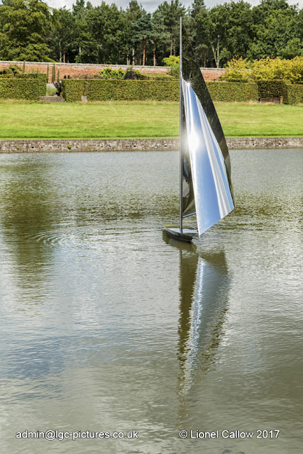 This is a stainless steel sculpture of a yacht. It is mobile with the wind floating on the lake.