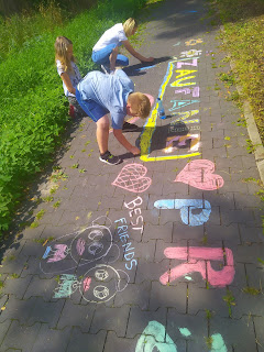 Dzieci rysujące kredą na chodniku.