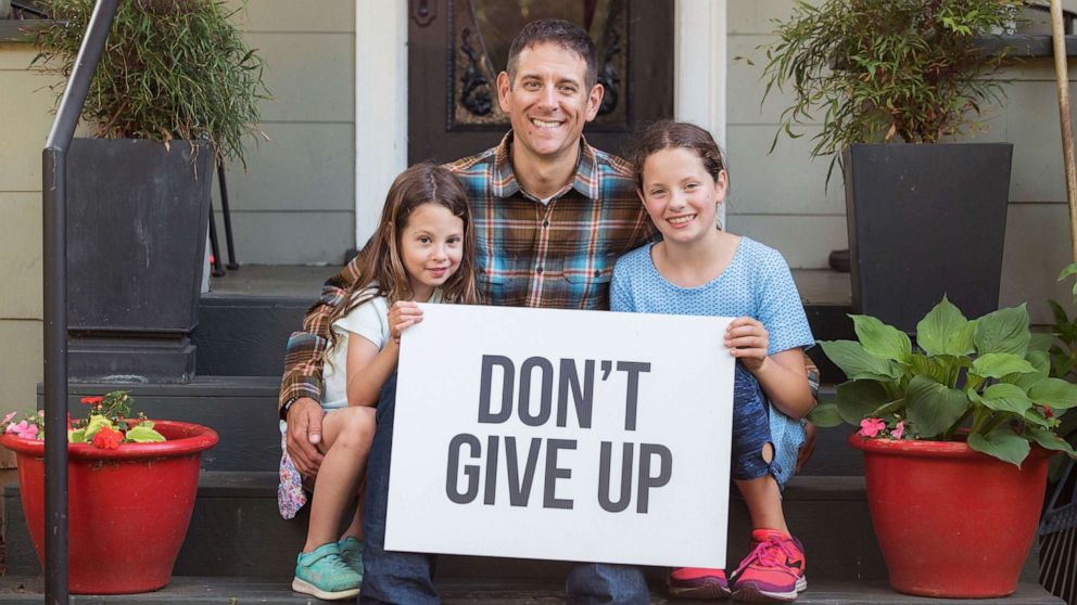 man sitting beside his two daughter