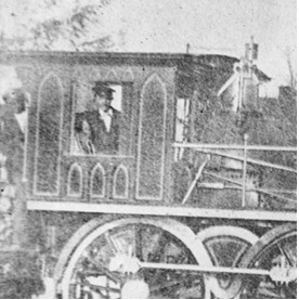 Photograph of a person in the engine of a 19th century train