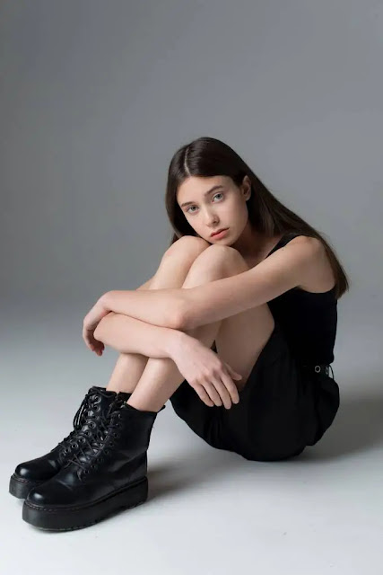 An image of a very beautiful girl sitting like the couch with black boots and red lipstick- sad girl dp