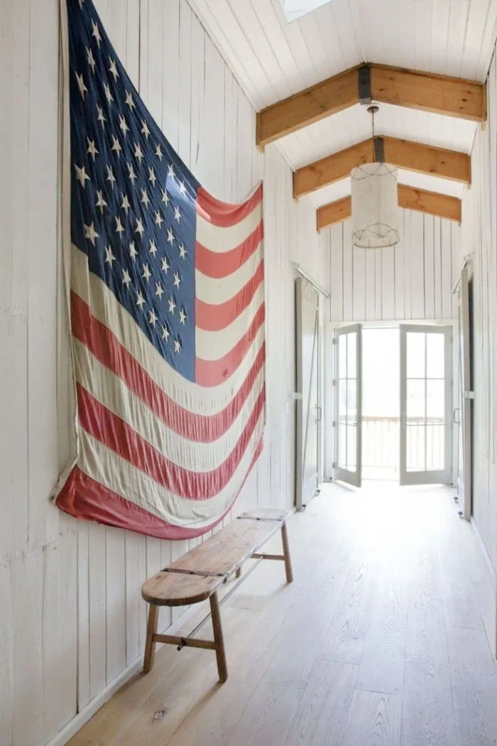 huge USA flag on white paneled wall, wood beams