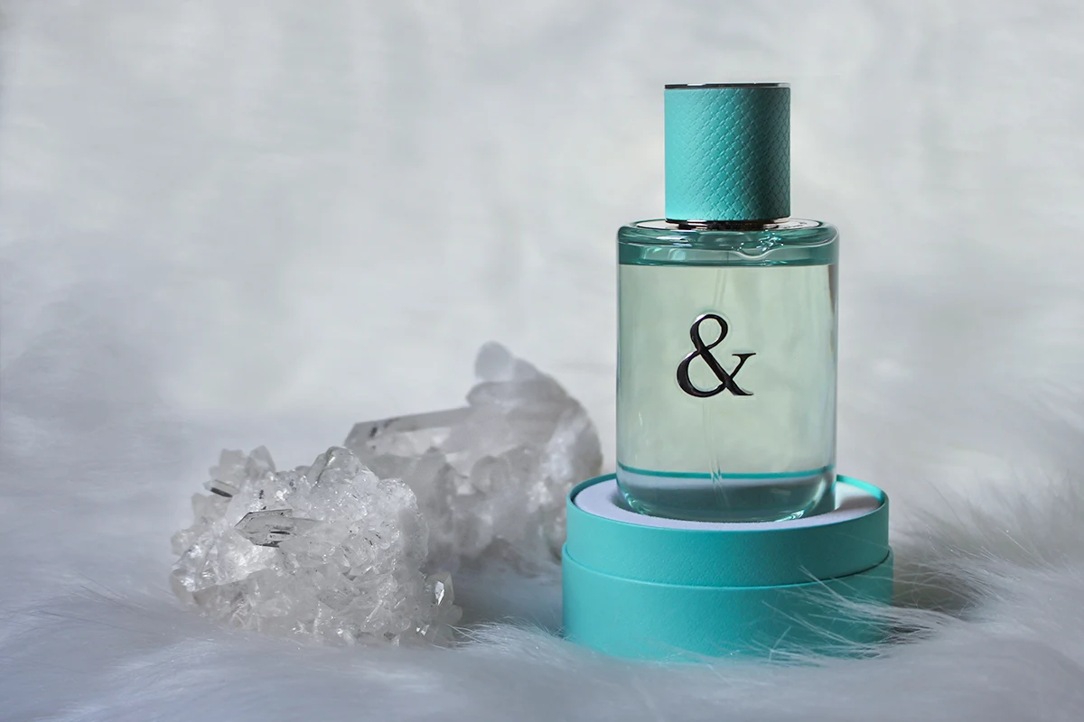 close-up studio shot of Tiffany & Co Love For Her Perfume tube on a white background surrounded by raw crystals