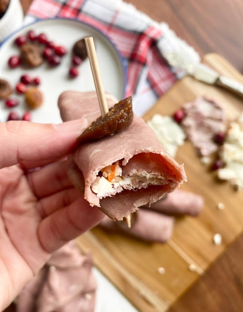 Hand holding a speared Fig & Goat Cheese Beef Roll Up