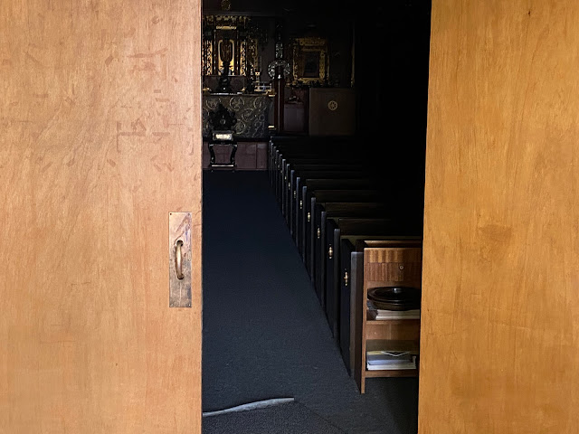 View of Amida Buddha statue through partially closed doors.