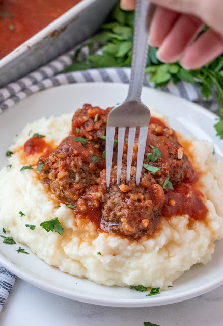 meatballs on a plate with mashed potatoes and a fork.