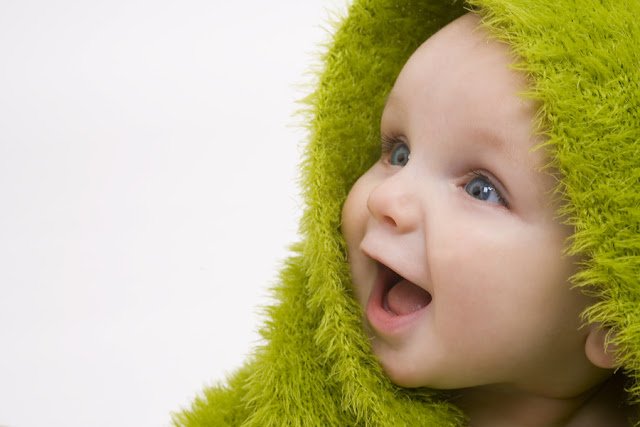 after bath baby picture under green towel and smiling widely