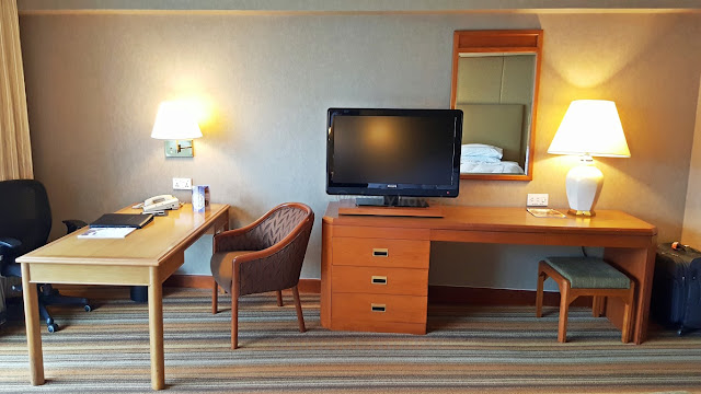 working desk and TV set in front of the beds at a room in Swissotel the Stamford, Singapore