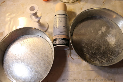 Two metal pans, spray paint and candleholder on a table