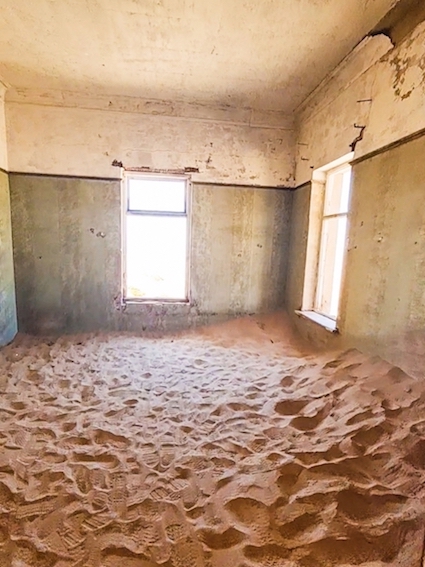 Sunlight hits the sand filling a room in the ghost town of Kolmanskop