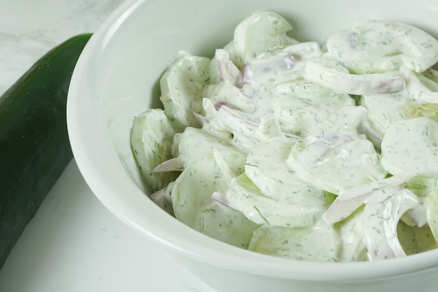 cucumber salad in a large white bowl.
