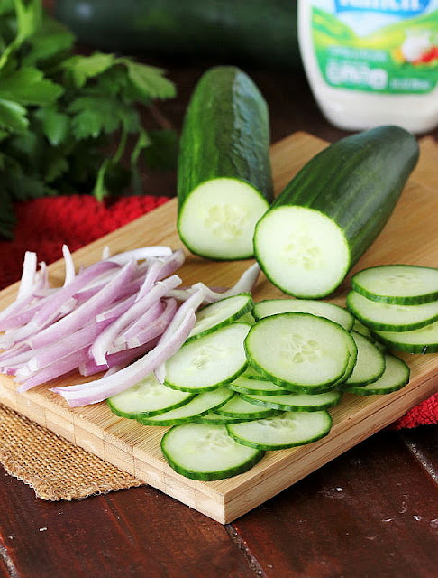 Thinly Sliced Cucumbers and Red Onion on Cutting Board Image
