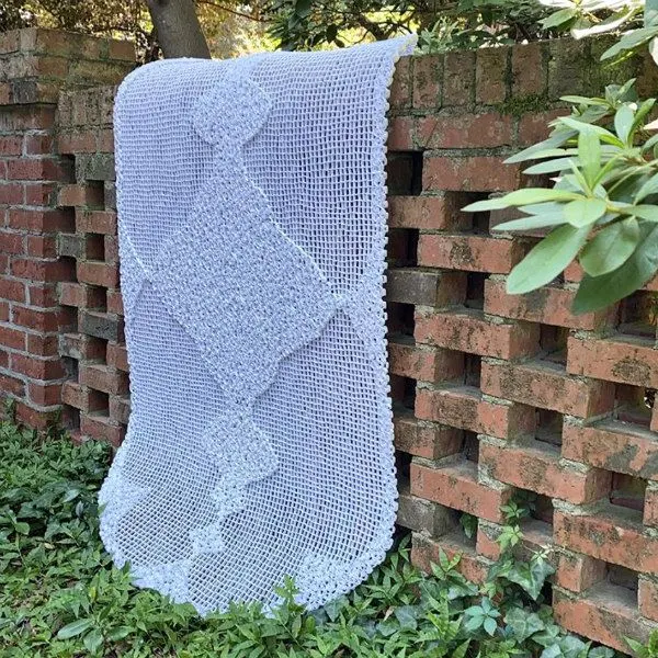 large-scale dimensional quilled paper lace displayed on brick wall