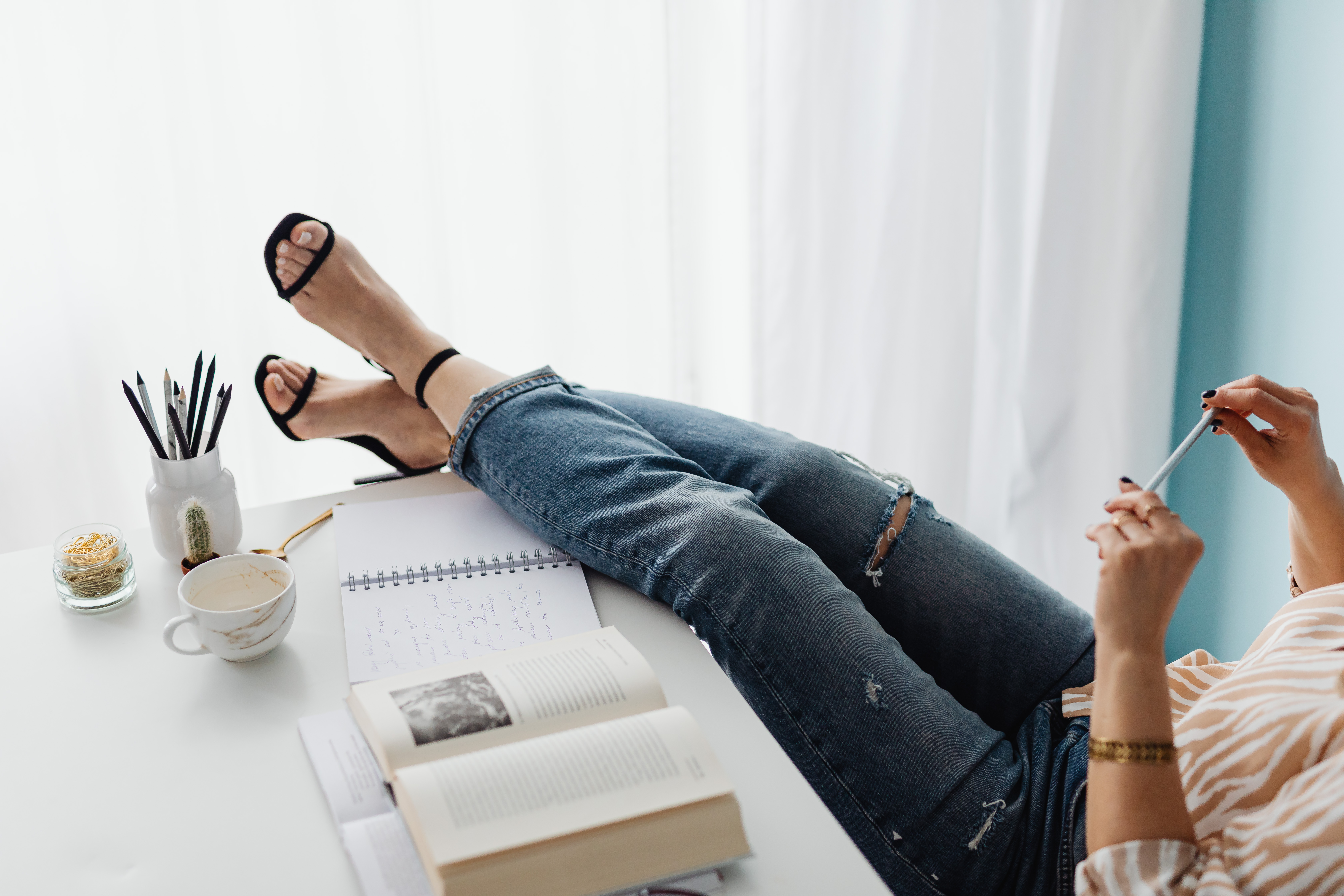 woman in a pair of distressed ripped jeans with her legs over the desk