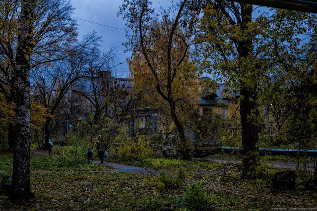 Женщина с ребенком в сумерках идет по тропинке в жилом районе