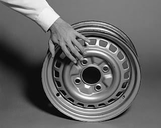 a foto 1 mostra parte de um braço de homem com camisa branca de punho e a esquerda mão sobre um aro (roda de automóvel); a 2 é uma fotomontagem na qual aparece uma perna de homem sentado e com a calça suspensa até o joelho de onde sai uma torneira, que aberta, deixa a água cair dentro de um balde de alumínio que está quase cheio; na foto 3 um homem (deduz-se pelas pernas de calças jeans e sapatos masculinos pretos de cadarço) parece andar sobre um caminho pavimentado de ovos de galinha brancos e inteiros; na foto 4 aparecem dois homens (pelas mãos e camisas de punhos brancos: um segura um pato malhado, grande e escuro e outro, um 