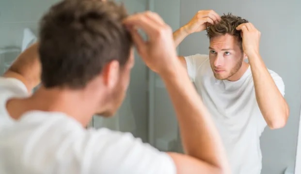 Uomo in bagno che si aggiusta i capelli