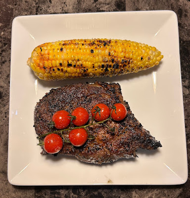 Rare grilled Angus ribeye with grilled corn on the cob with elote spice