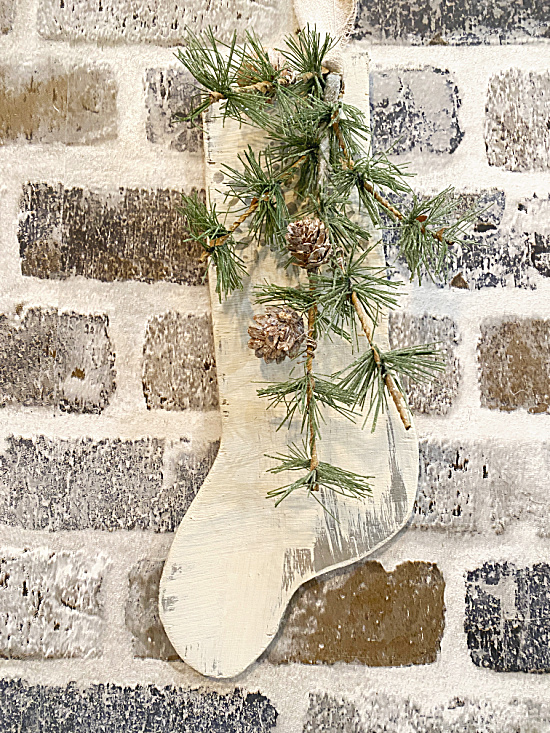 wooden stocking with greens on brick wall