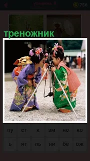  две девочки в кимоно стоят около треножника с фотоаппаратом