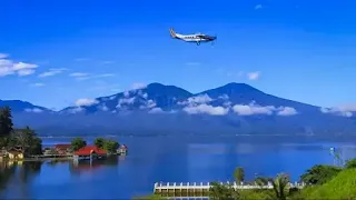 A plane soaring over a serene lake with majestic mountains in the backdrop.