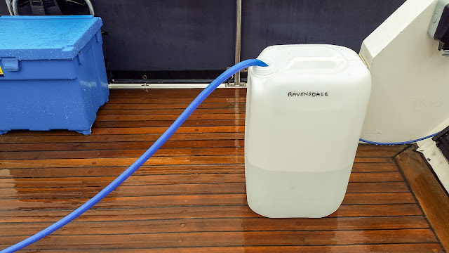 Photo of filling a jerry can with water on our very wet aft deck