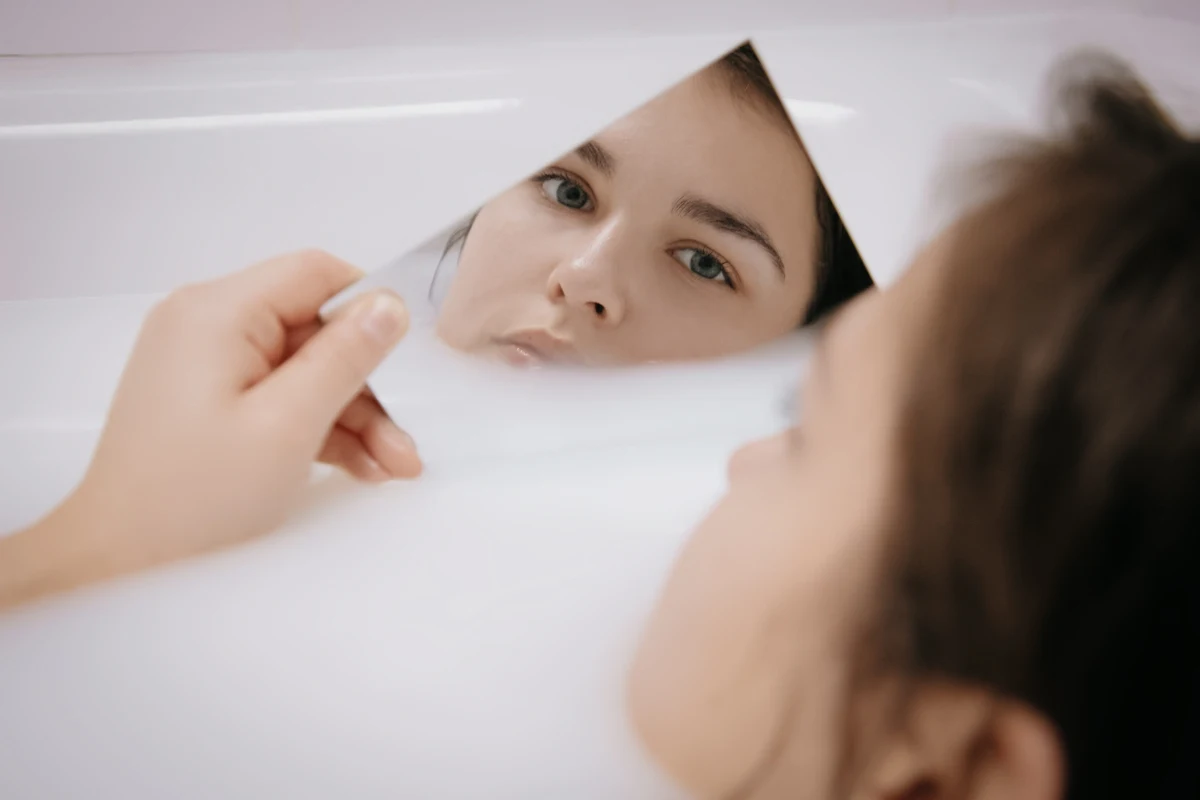 portrait of a woman looking into the mirror in a bathtub